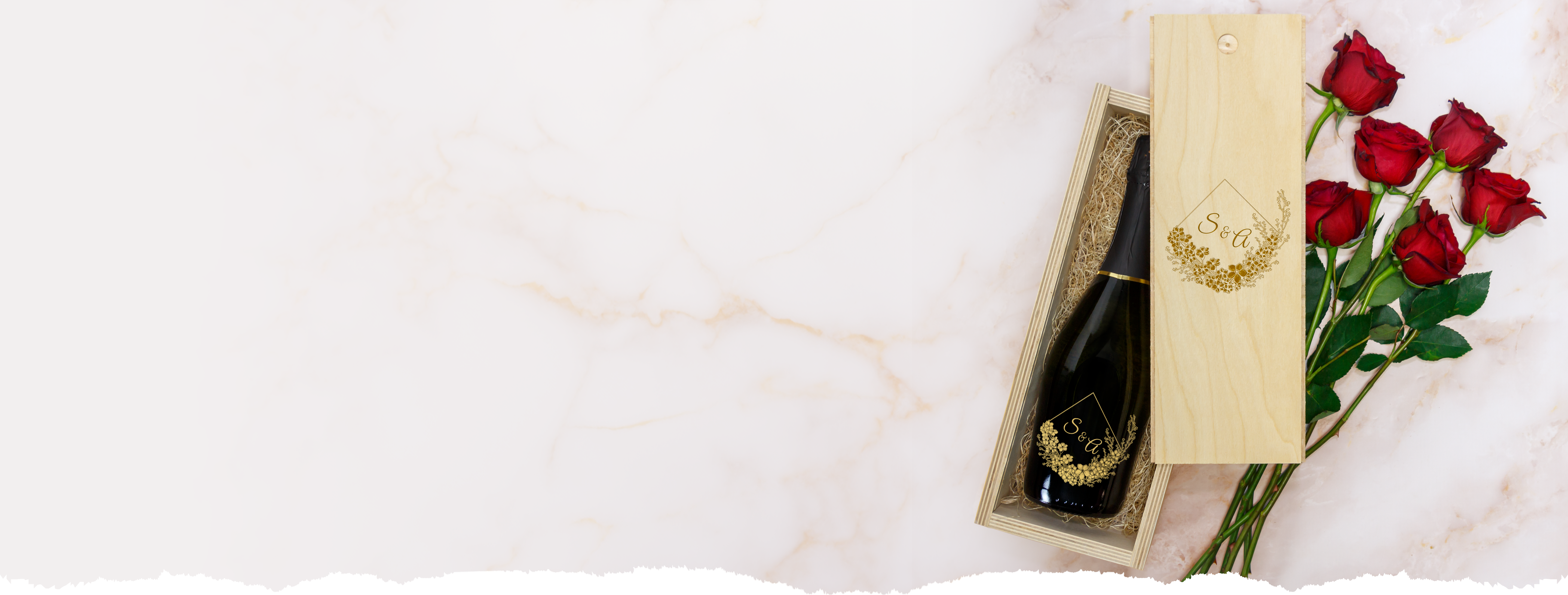 Bottle of champagne in a wooden box with red roses on a marble surface