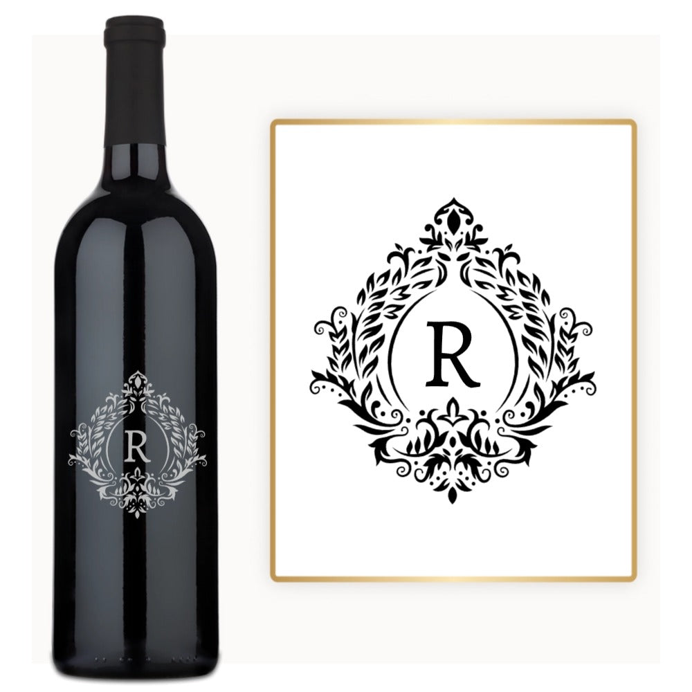 A wine bottle with an engraved ornate letter R and a matching decorative R printed on a paper label.