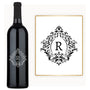 A wine bottle with an engraved ornate letter R and a matching decorative R printed on a paper label.