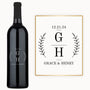 A wine bottle engraved with “12.21.24, G H, Grace & Henry” and decorated with leafy accents.