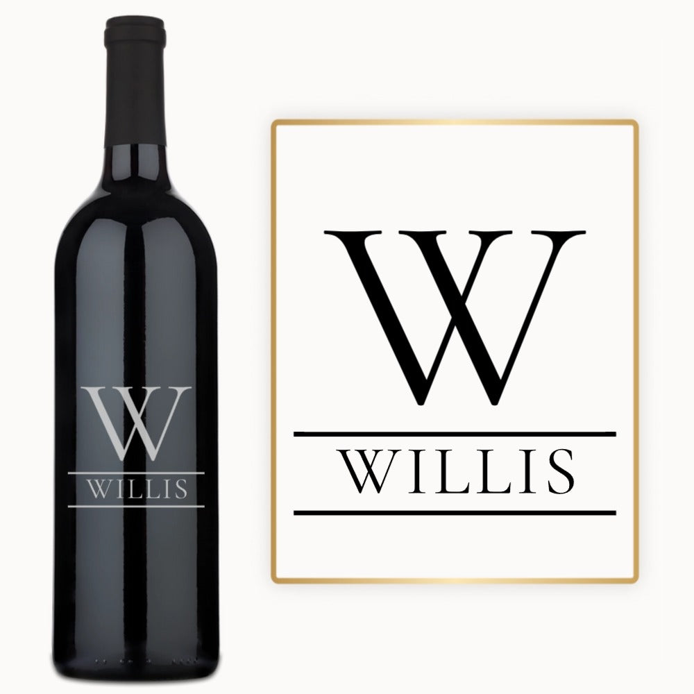 An engraved wine bottle sits next to a matching sign, both showing a split initial and personalized name.