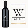 An engraved wine bottle sits next to a matching sign, both showing a split initial and personalized name.