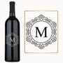 A wine bottle with a circular M monogram engraved on the label next to a matching card.