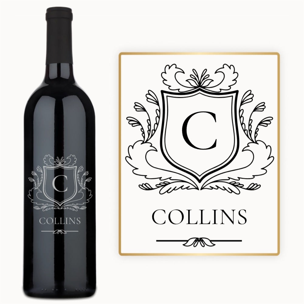 A wine bottle and card feature a Heritage Shield Monogram engraved with the letter C and the name COLLINS.