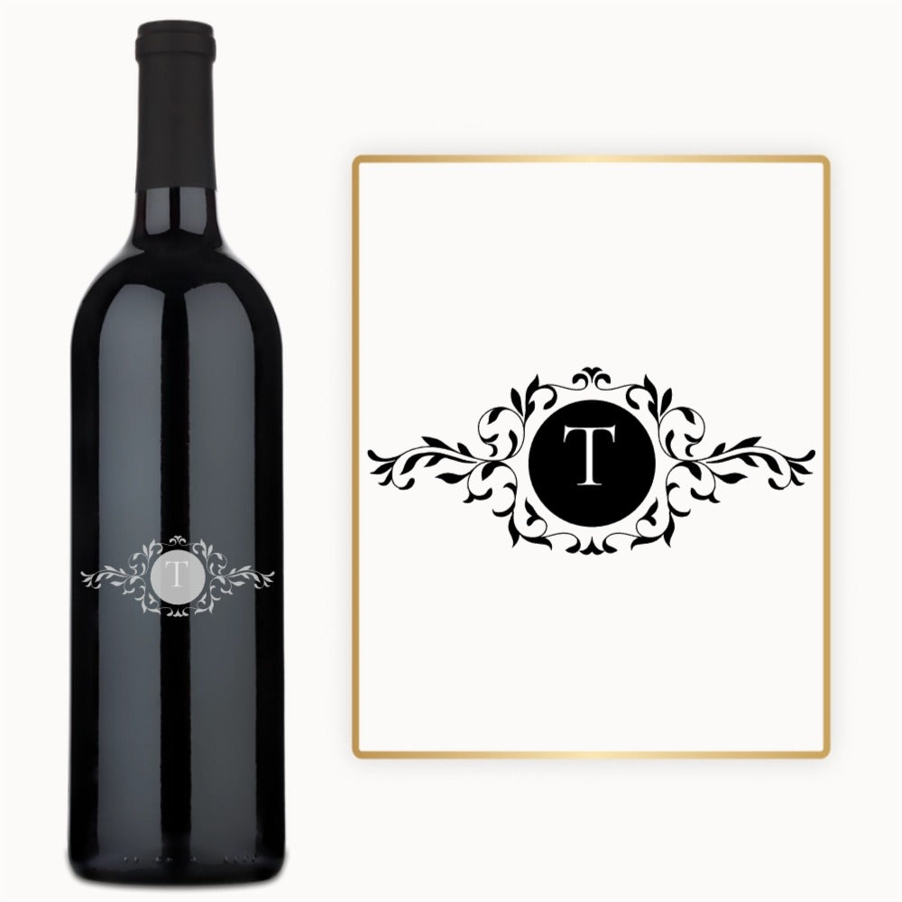 A wine bottle with a white letter T and floral patterns engraved inside a black circle on the label.