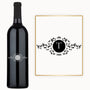 A wine bottle with a white letter T and floral patterns engraved inside a black circle on the label.