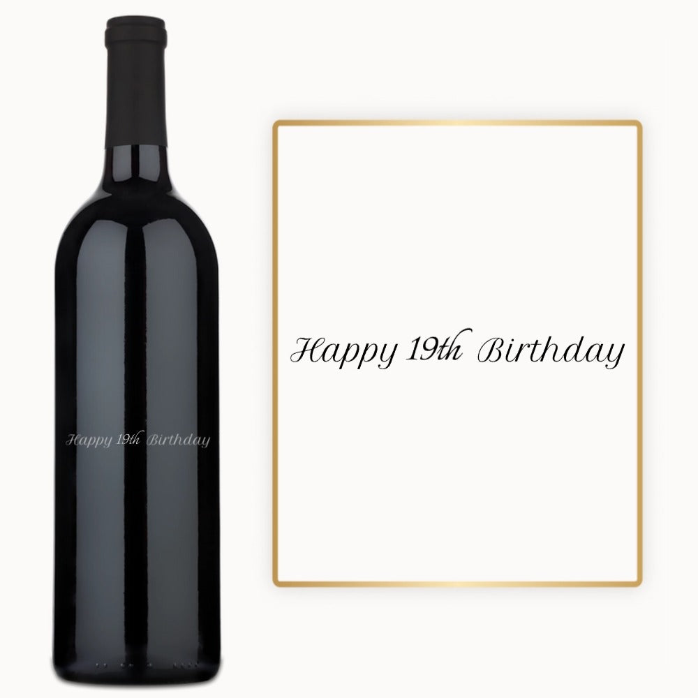 A wine bottle with custom engraving and a Happy 19th Birthday card beside it.