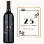 A wine bottle with 25 years - July 8, 1999 engraved, framed by black leaves on the label.