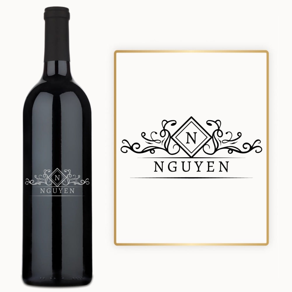 A custom-engraved wine bottle with a diamond crest monogram sits next to a matching monogrammed name card.