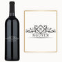 A custom-engraved wine bottle with a diamond crest monogram sits next to a matching monogrammed name card.