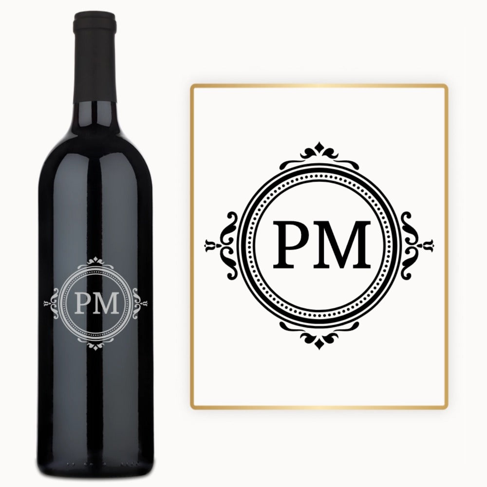 A wine bottle with a circular monogram sits next to matching monogrammed white paper.
