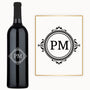 A wine bottle with a circular monogram sits next to matching monogrammed white paper.