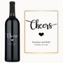A wine bottle engraved with Cheers, a heart symbol, and custom names with a date on the label.