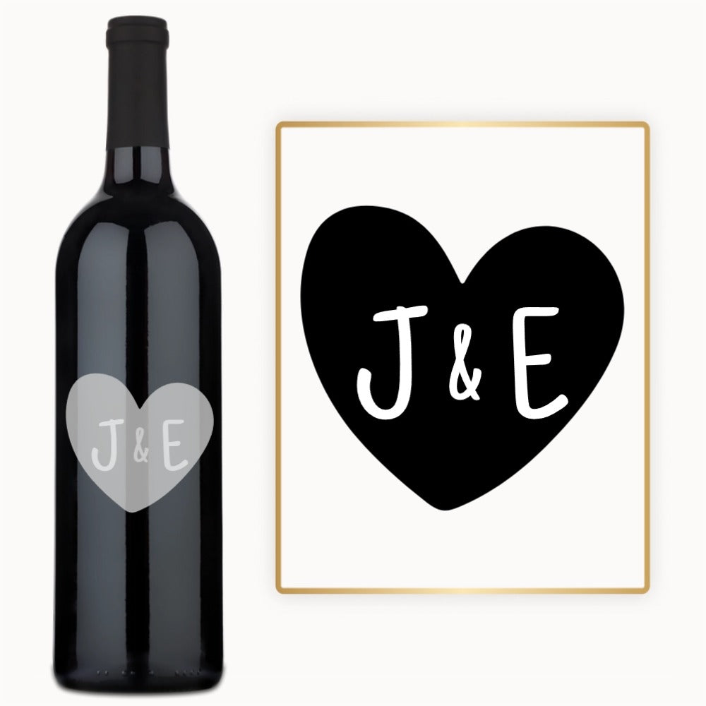 A wine bottle engraved with a heart monogram and the initials J & E, presented as an anniversary gift.