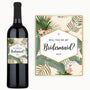 A wine bottle with a custom label featuring tropical designs, intended as a bridesmaid proposal gift.
