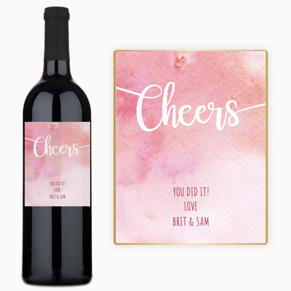 A bottle of Pink Cheers Celebration wine with a custom label and a card that reads, You did it Love, Brit & Sam.
