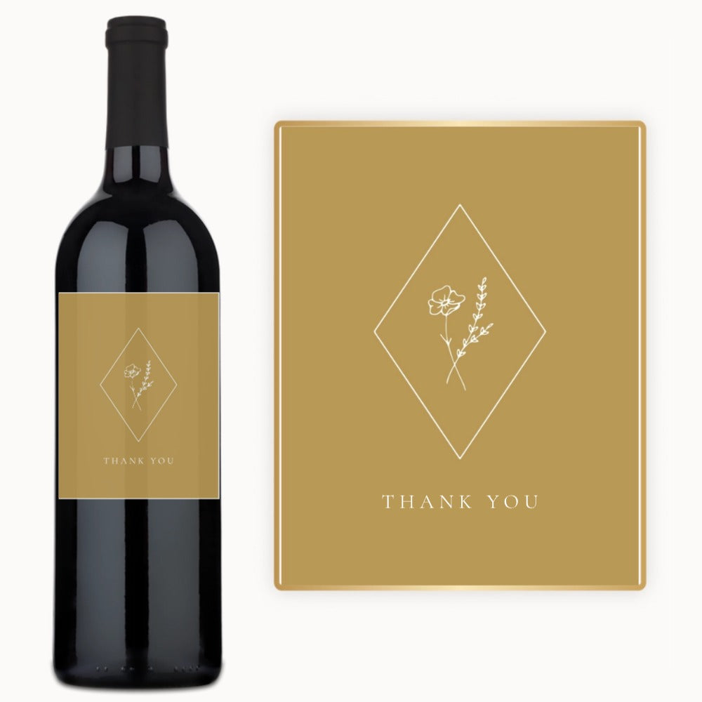 A wine bottle with a floral label and a thank you card, both set on a tan background.