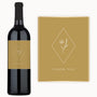 A wine bottle with a floral label and a thank you card, both set on a tan background.