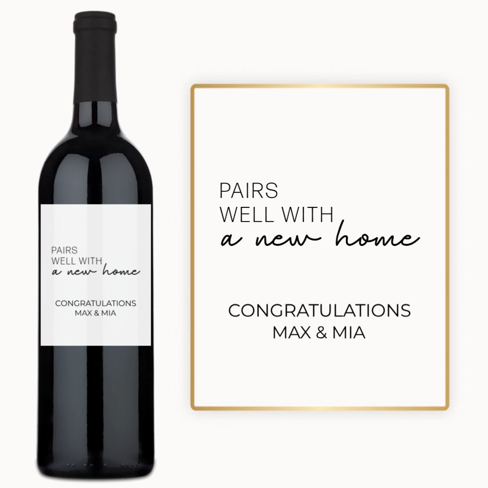 A bottle of wine with a custom label reading “Pairs Well With a New Home,” alongside the names Max & Mia.