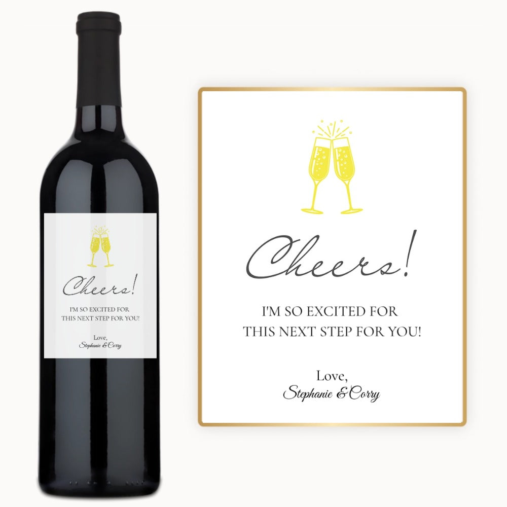 Two wine glasses labeled Cheers clink together beside a custom-labeled wine bottle and a card with clinking glasses.