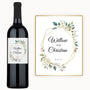 A wine bottle with a custom label featuring floral and geometric designs and personalized names.
