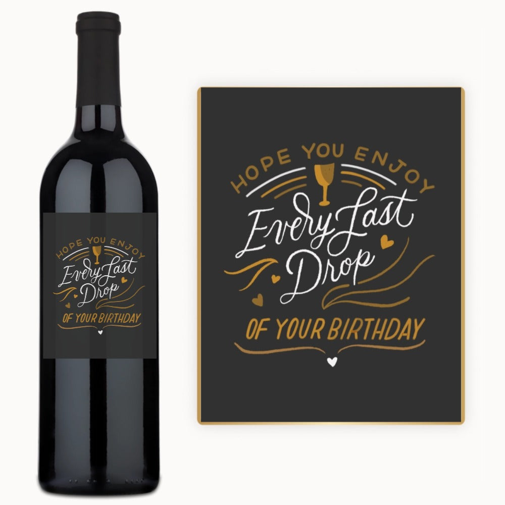 A wine bottle with a custom label and card, both displaying white and gold birthday wishes.