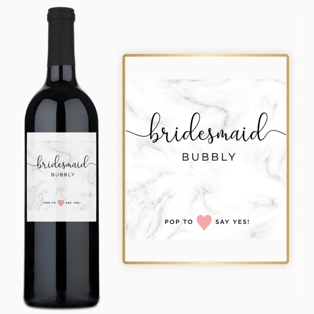 A wine bottle with a custom marble label reading Pop to ♥ say yes, ideal for bridal gifting.