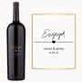 A custom Just Engaged wine bottle next to an engagement card for Cassie & James, dated 4.24.23.