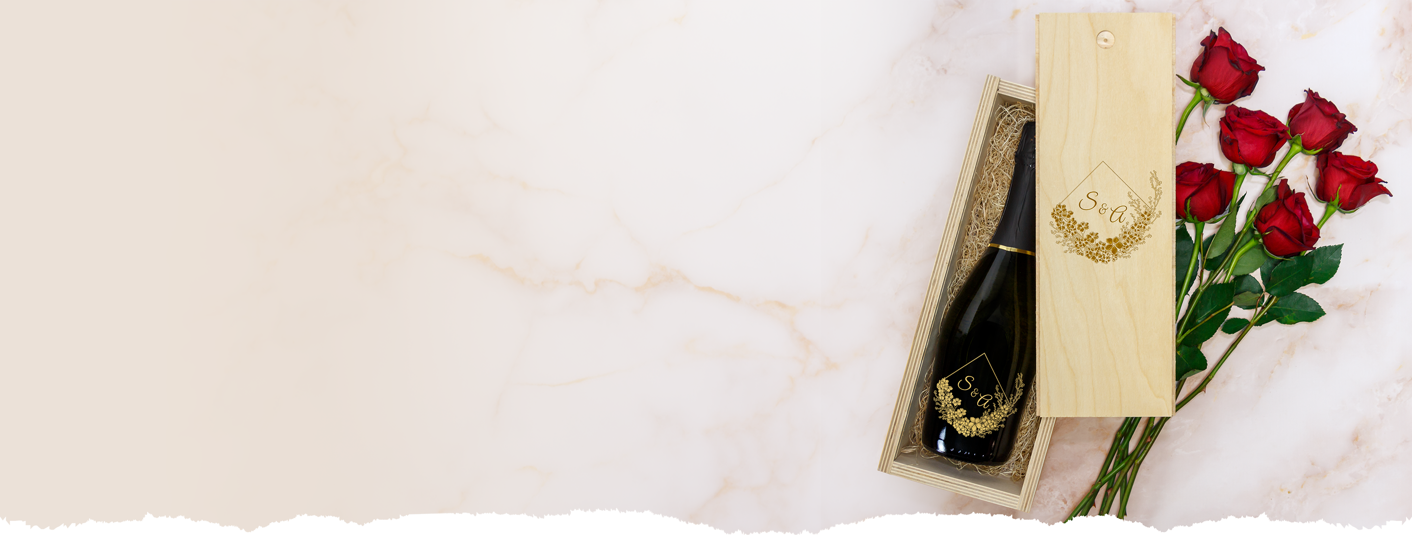 Bottle of champagne in a wooden box with red roses on a marble surface