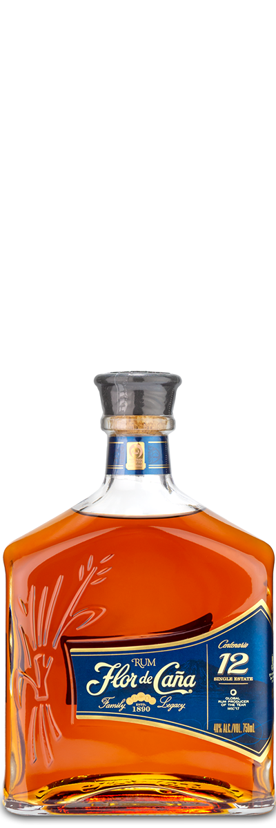 A custom-engraved FLORDECANA Flor de Cana 12 Year Rum bottle with amber liquid and a blue label on white background.