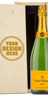 A Veuve Clicquot champagne bottle in a wood gift box with an engraved lid showing personalized text.
