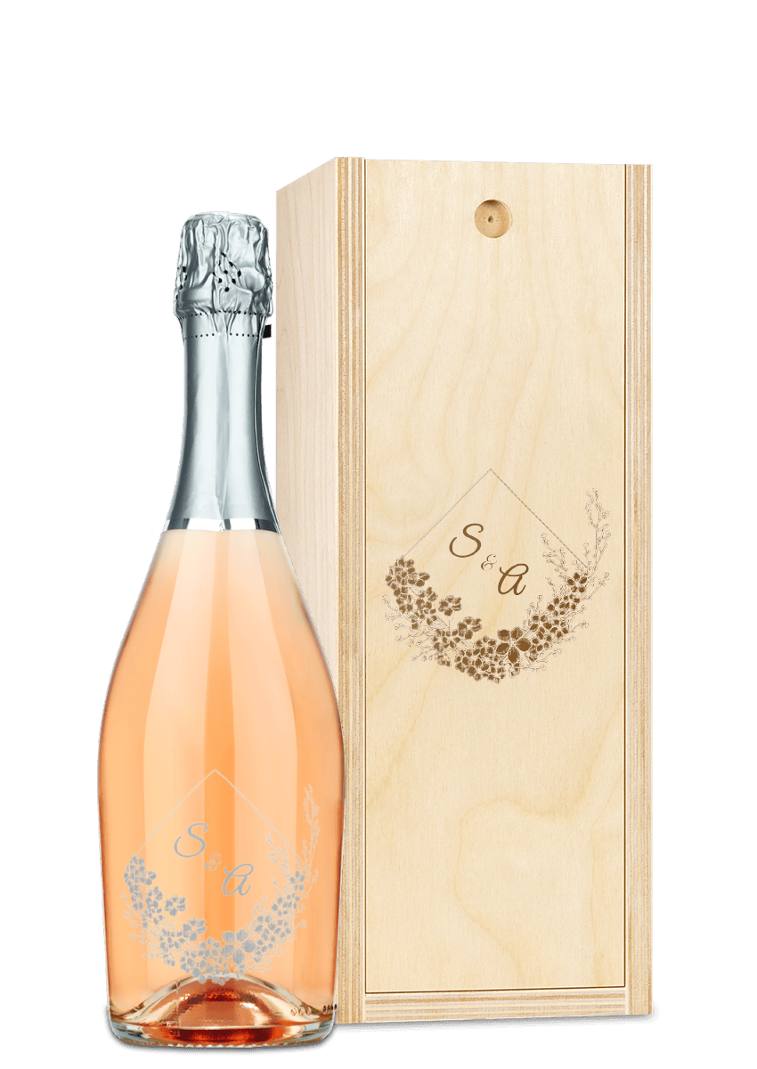 A wine bottle with a floral label alongside a wooden box engraved with matching floral designs.