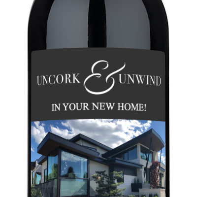 A bottle of wine with a custom label reading Uncork & Unwind, presented as a housewarming gift.