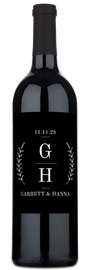 A wine bottle featuring a monogram label with laurel branches, conveying an elegant, nature-inspired design.