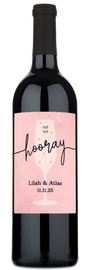 Wine bottle with a pink label displaying names, a date, and an illustration of a champagne glass.