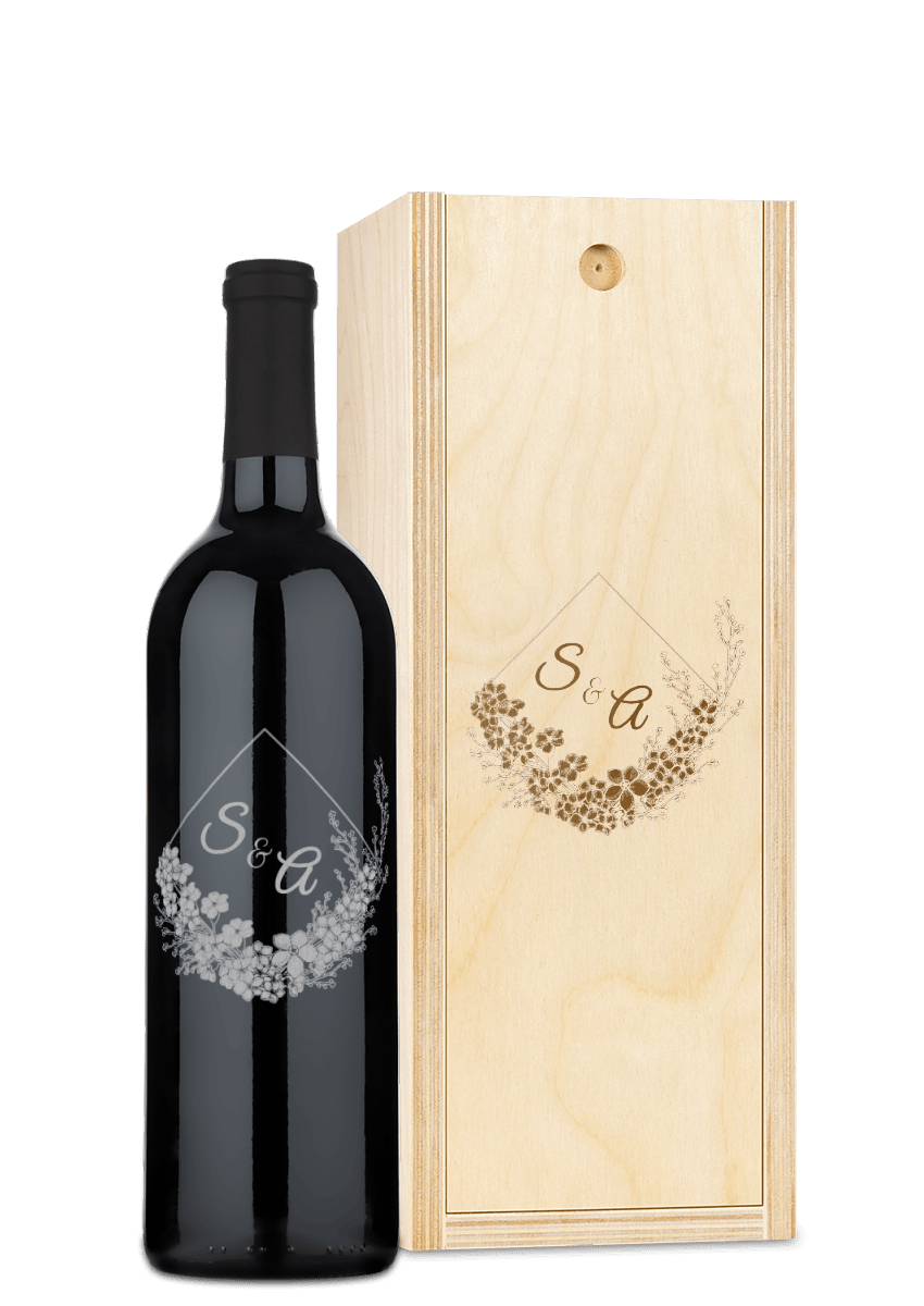 A wooden wine box with engraved floral patterns and the initials S & A on its lid.