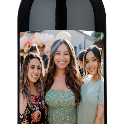 Personalized wine bottle with a label showing three women and the text “Happy Birthday XOXO.”.