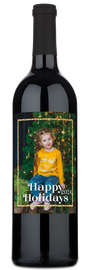 Child in yellow stands by a tree, with Happy Holidays 2024 text. Gold frame wine label visible.