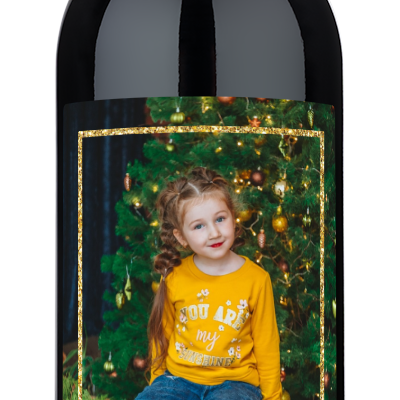 Child in yellow stands by a tree, with Happy Holidays 2024 text. Gold frame wine label visible.