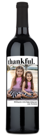 Two smiling girls outdoors on a wine bottle label with thankful in script and a holiday photo.