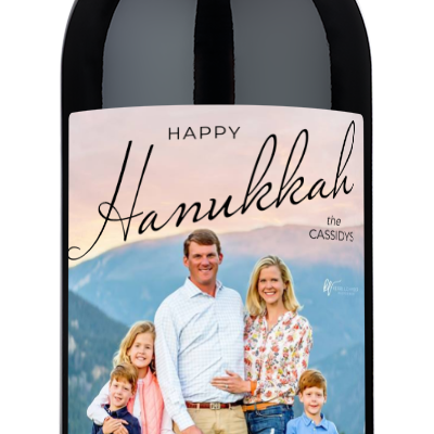 A wine bottle with a Hanukkah-themed label featuring a family photo and space for a personalized holiday message.