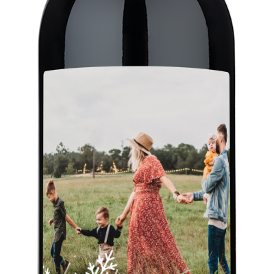 Custom wine bottle with festive snowflake label and photo, designed for Christmas gifting.